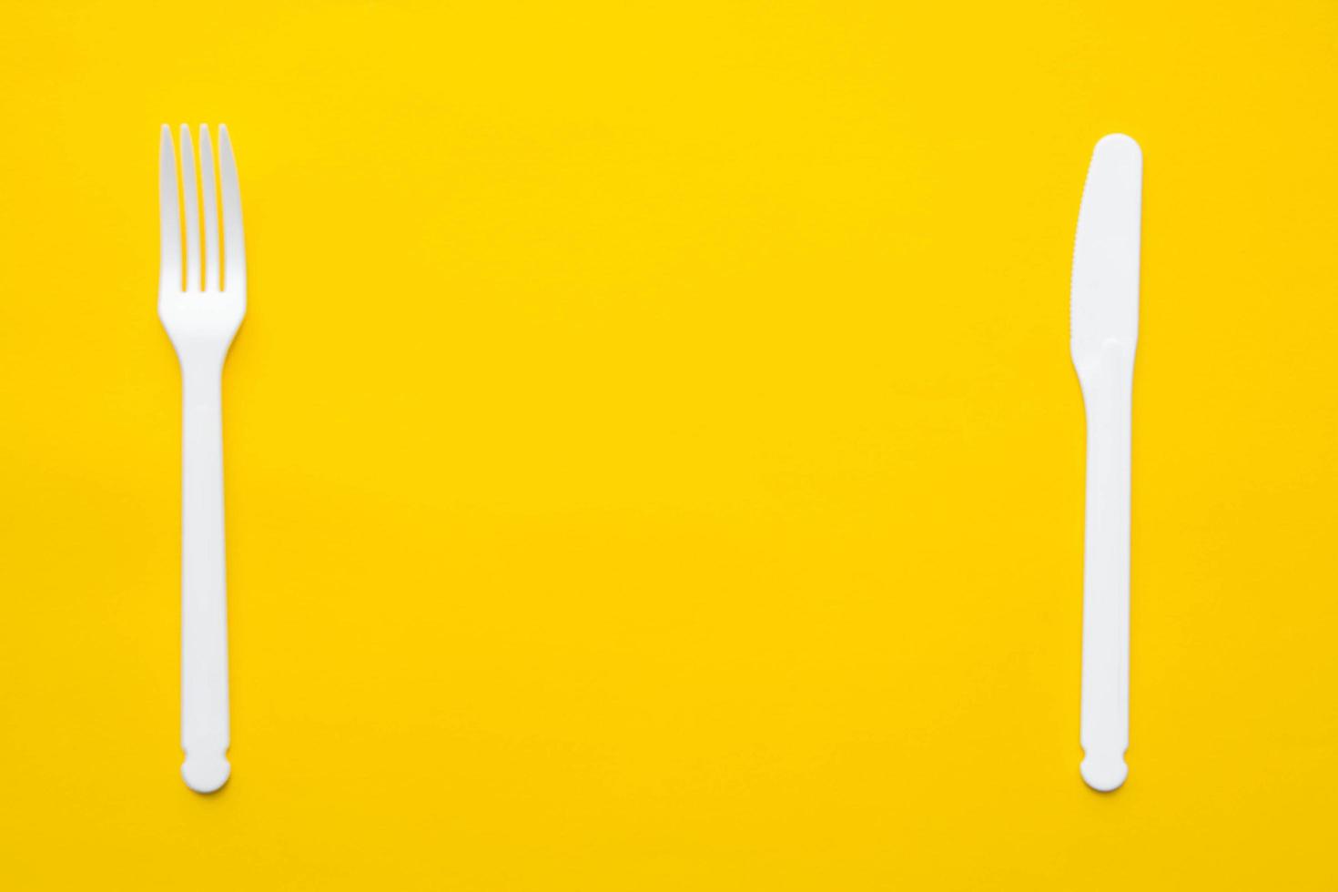 plast vit gaffel och kniv på gul bakgrund foto