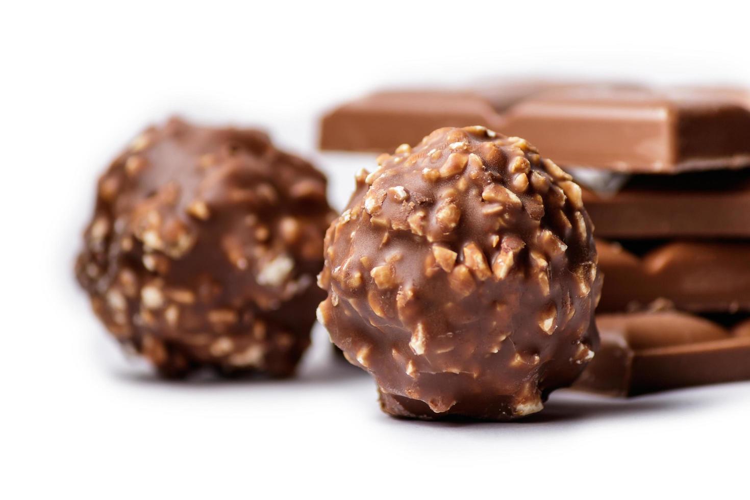 selektiv fokusering av chokladbonbon täckta med nötter med chokladkakor i bakgrunden foto