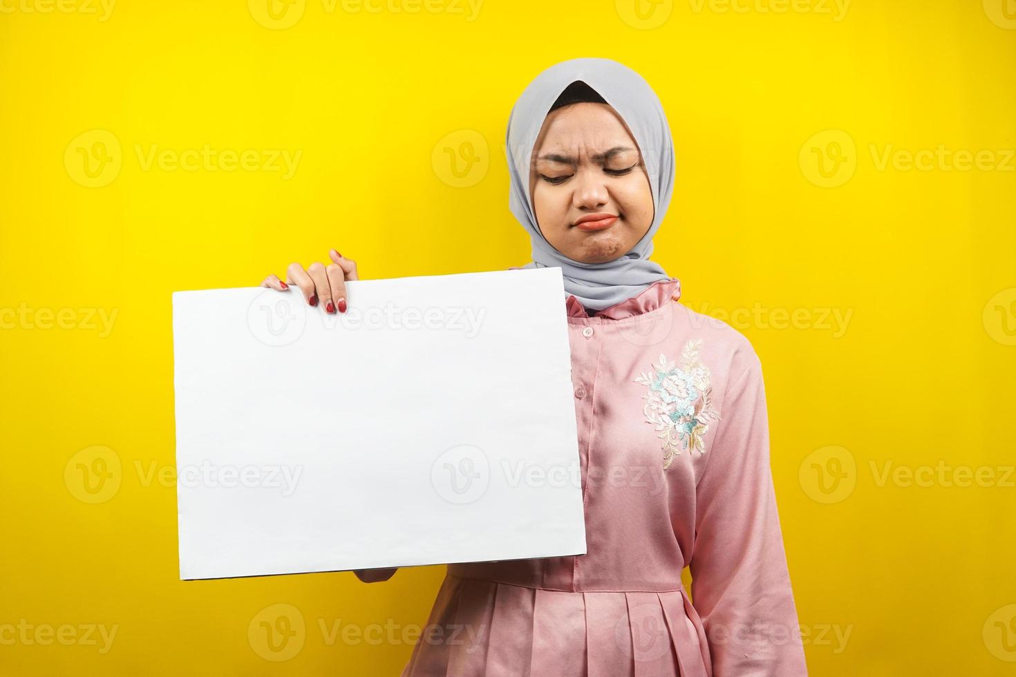 ganska ung muslimsk kvinna ledsen, hand som håller en tom banderoll, plakat, vit tavla, tom skylttavla, vit reklamtavla, presenterar något i kopieringsutrymmet, marknadsföring foto