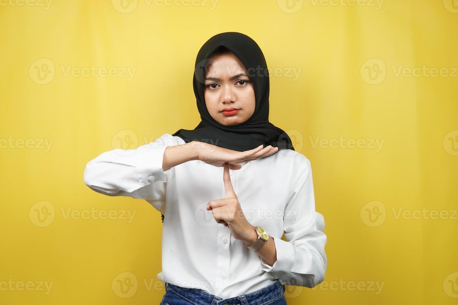 vacker asiatisk ung muslimsk kvinna med hand som visar stoppskylt, tyst tecken hand, talar inte tecken hand, gör inte oväsen tecken hand, isolerad på gul bakgrund foto