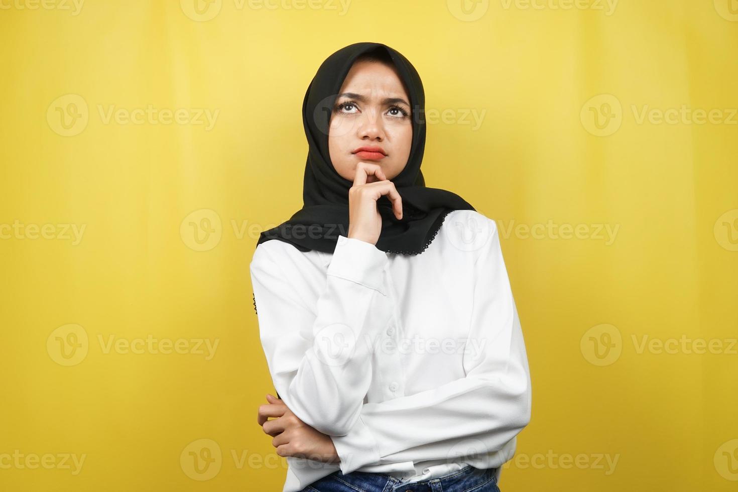 vacker asiatisk ung muslimsk kvinna som tänker, letar efter idéer, letar efter lösningar på problem, med händer som håller hakan, isolerad på gul bakgrund foto