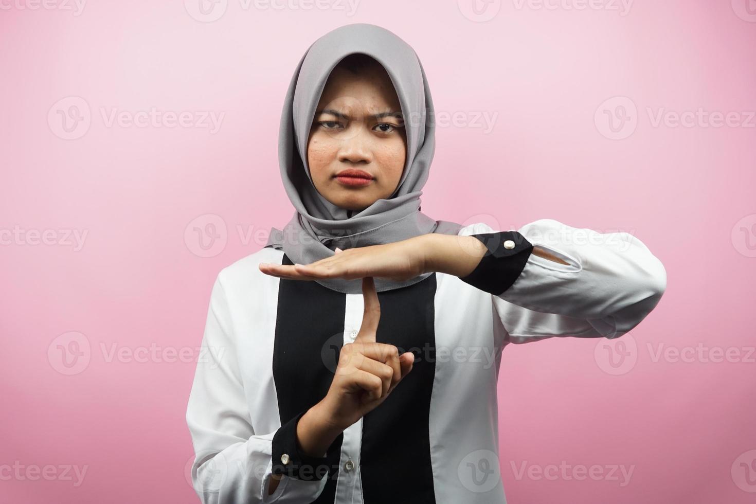 vacker asiatisk ung muslimsk kvinna med hand som visar stoppskylt, tyst tecken hand, talar inte tecken hand, gör inte oväsen tecken hand, isolerad på rosa bakgrund foto