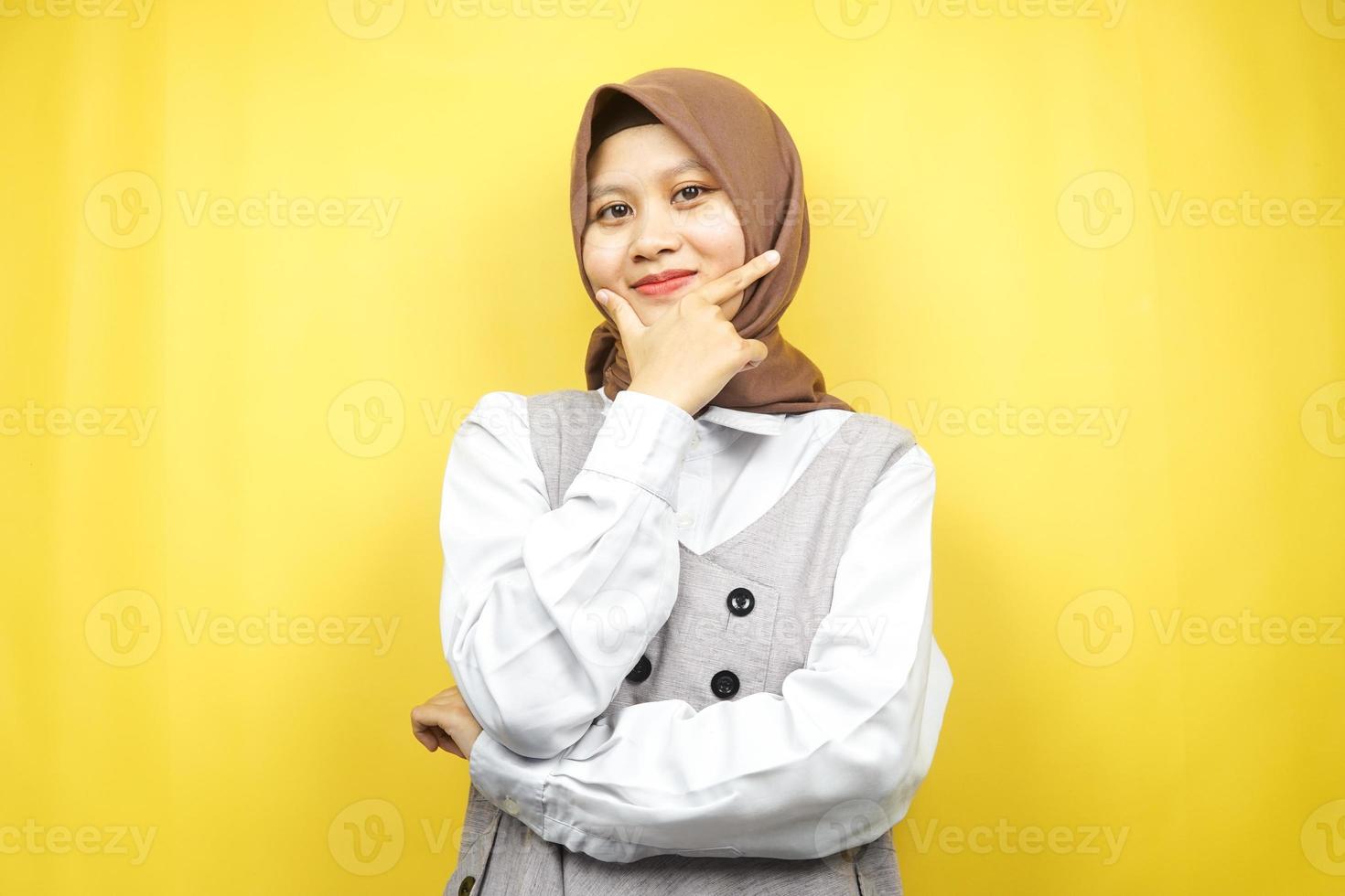 vacker ung asiatisk muslimsk kvinna som ler självsäker, entusiastisk och glad med händerna v-tecken på hakan isolerad på gul bakgrund foto