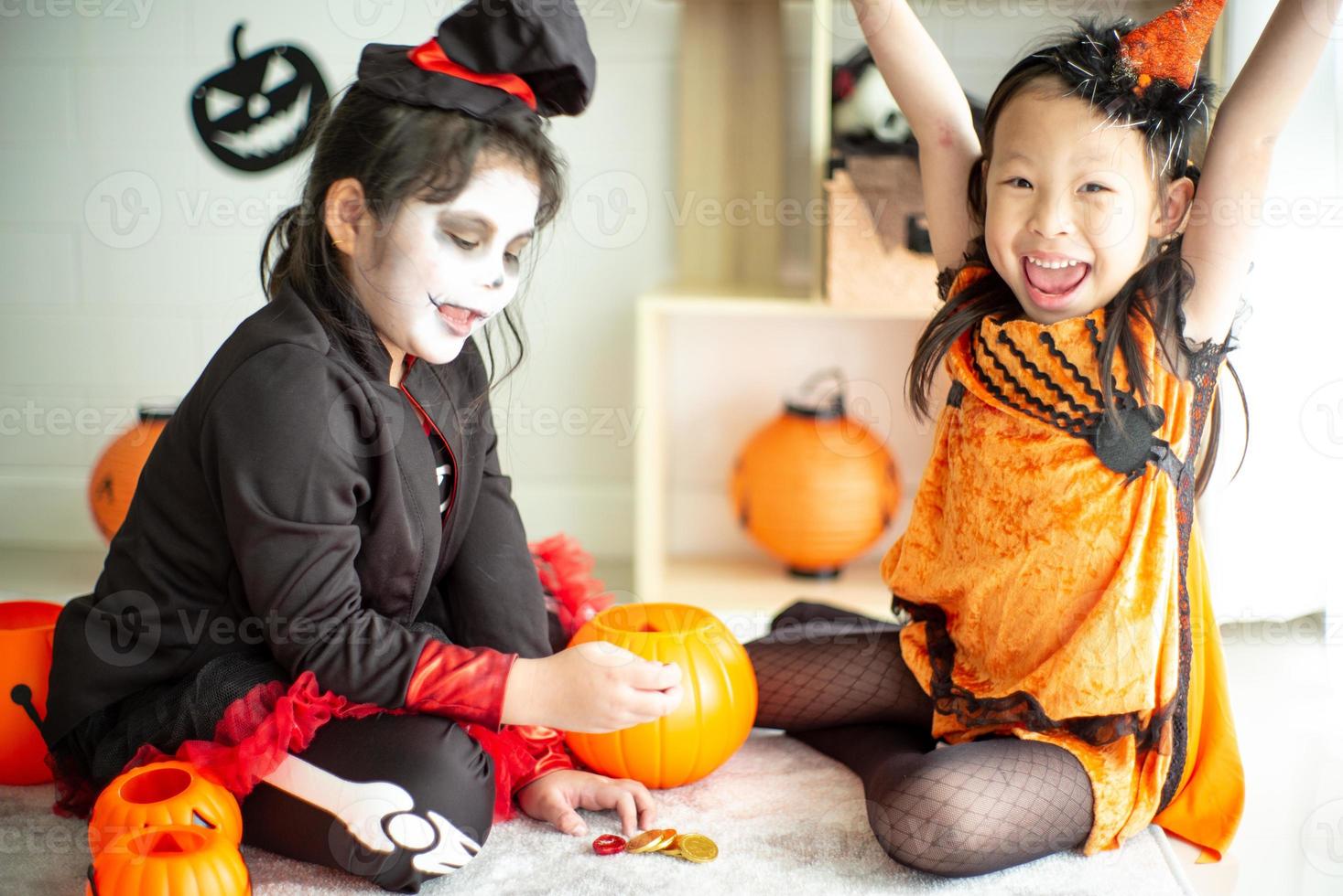 porträtt av två glada systrar i halloween-kostymen som delar godiset och chokladen från trick or treat foto