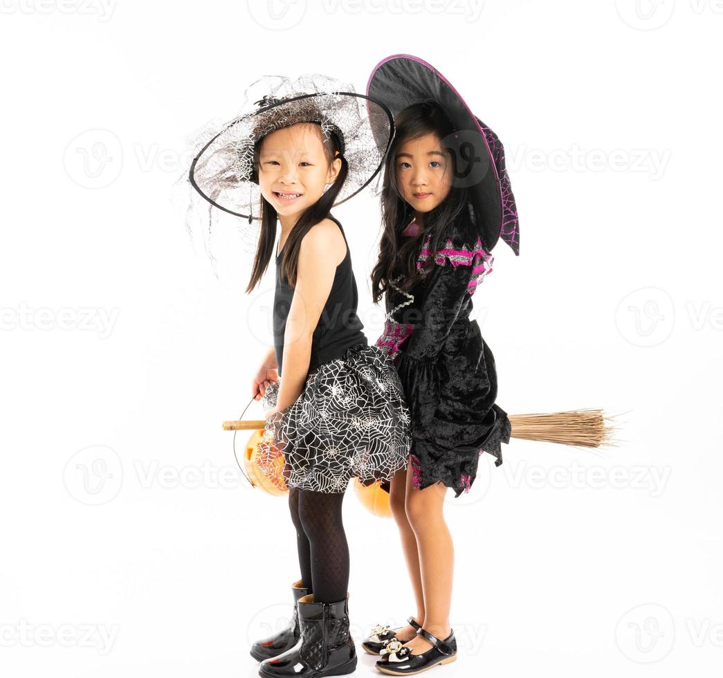 porträtt asiatiska flickor i halloween kostym rider på kvasten tillsammans och håller pumpan med isolerad bakgrund foto