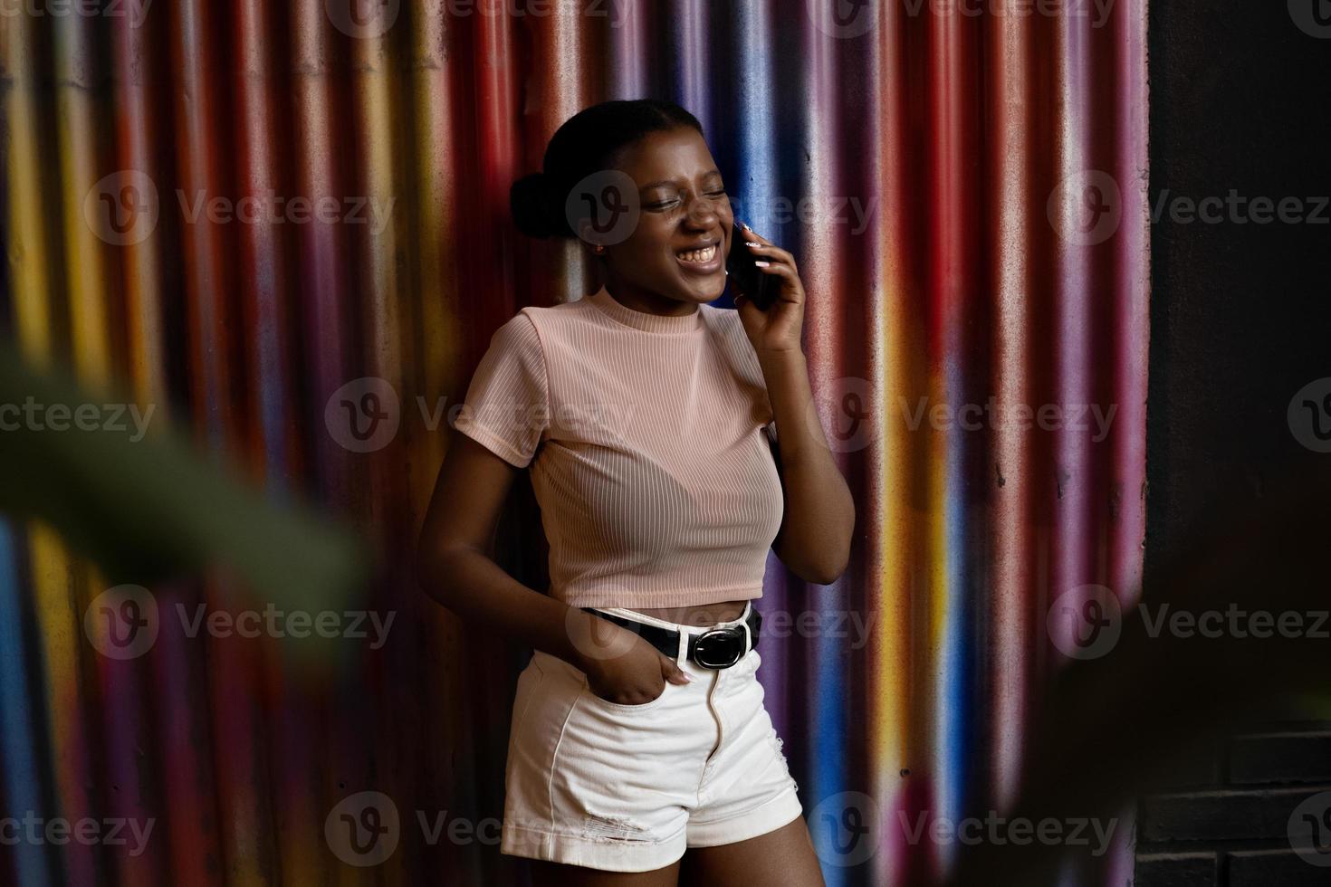 leende ung afroamerikansk kvinna pratar med mobiltelefon foto