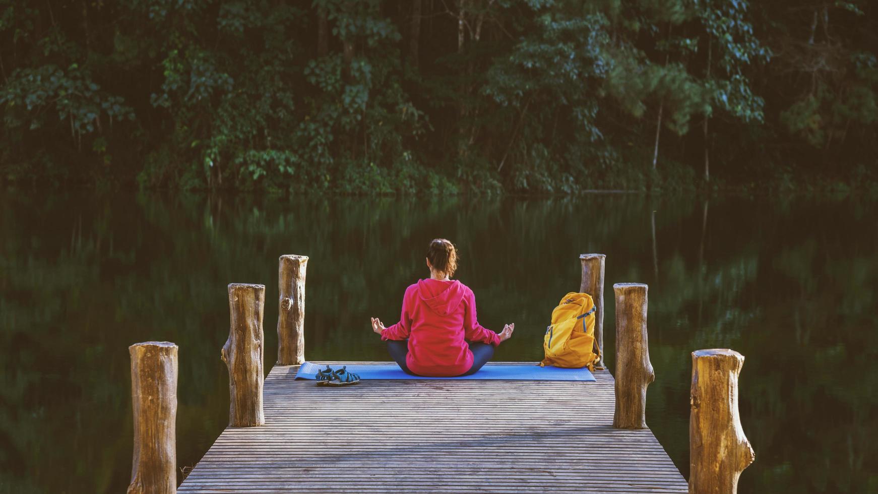 asiatiska kvinnor koppla av i semestern. spela om yoga. på berget, träna, leka yoga på bambubron bredvid sjön i dimman i pang ung, thailand. foto