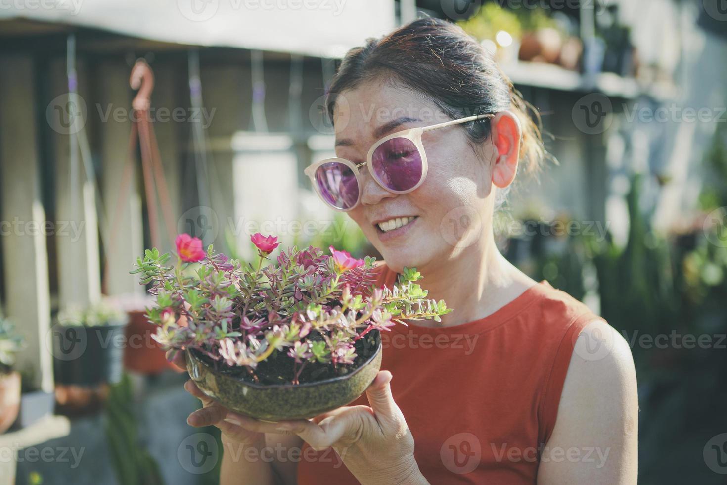 vacker kvinna höja kruka av blommande blomma med lycka ansikte foto