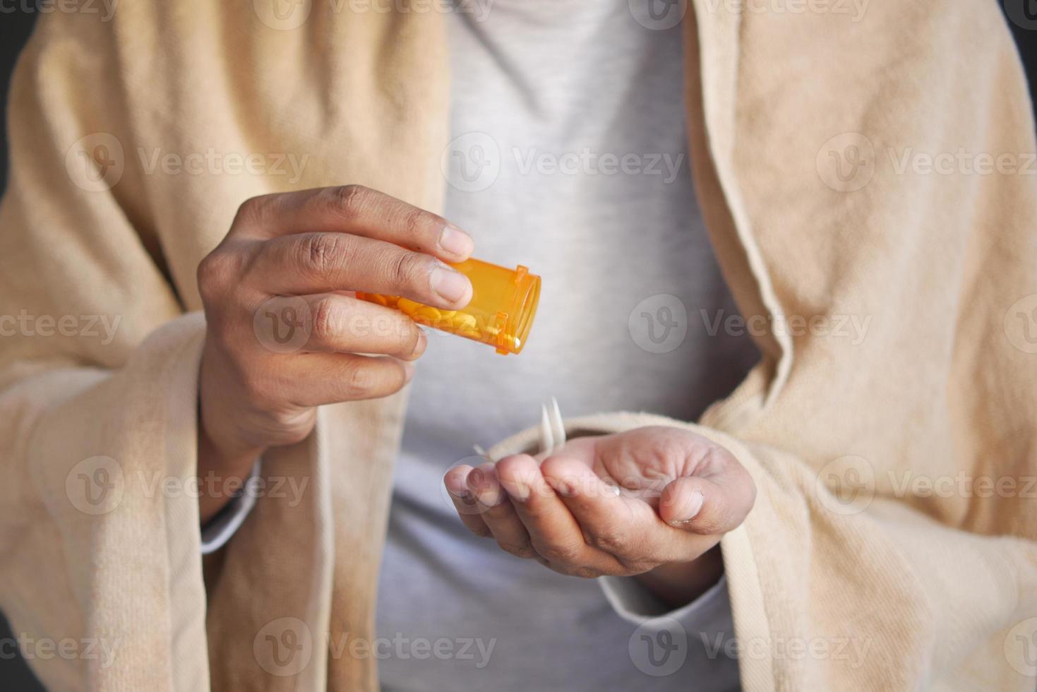 mans hand med medicin som spillts ut ur pillerbehållaren foto