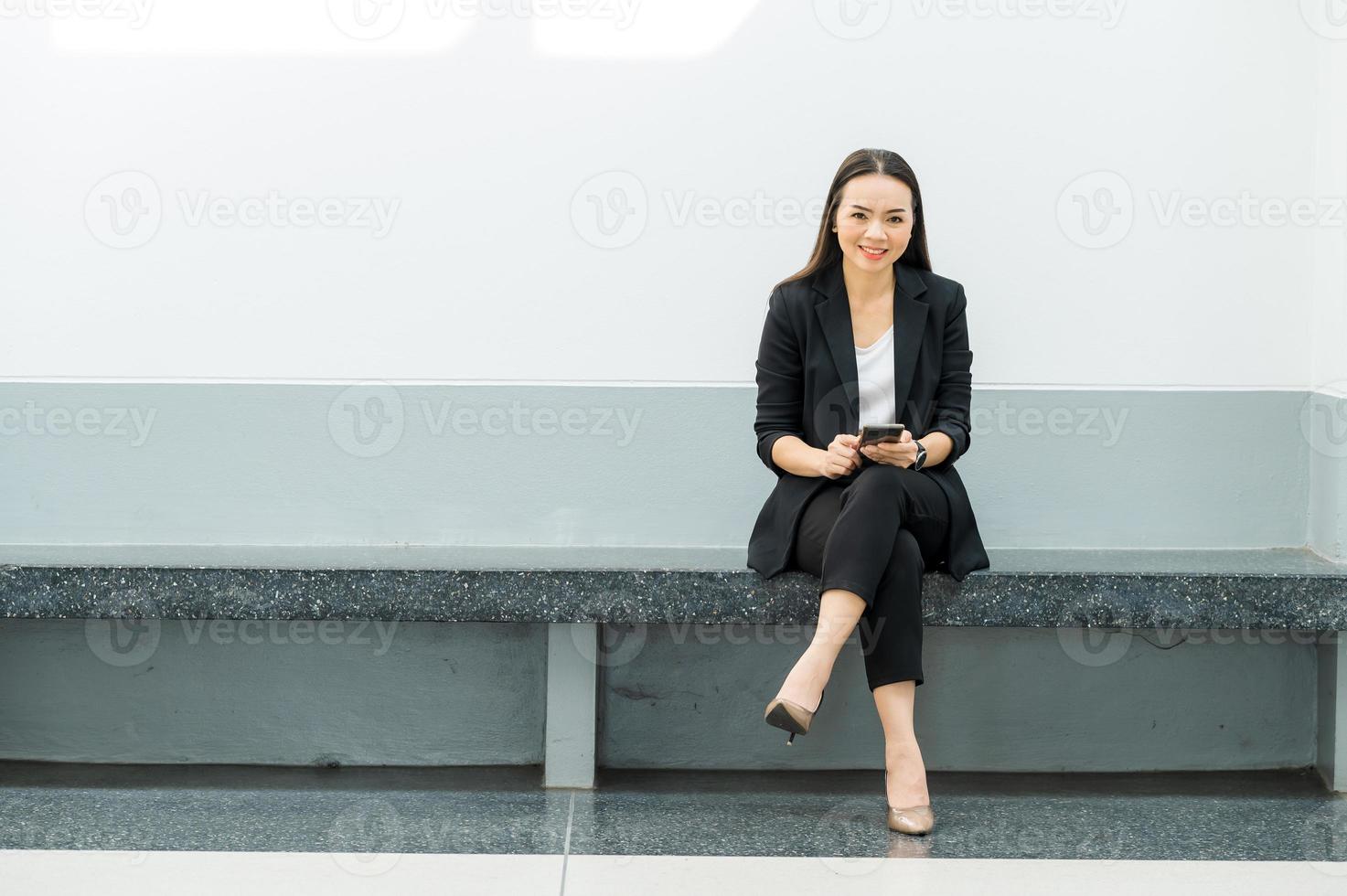 asiatisk arbetande kvinna som håller en mobiltelefon står på kontoret arbetar kvinna koncept affärskvinna i klassrumsteknik foto