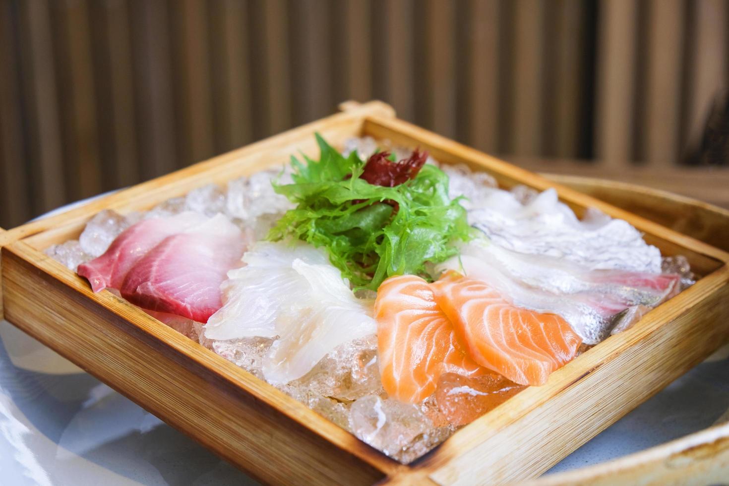 japansk mat sashimi lax och rå fisk sashimi sallad på is serveras på trä bricka i den japanska matrestaurangen foto