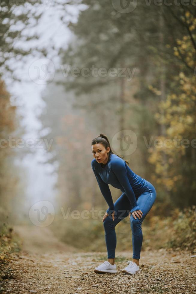 ung kvinna ta en paus under utomhusträning på skogsstigen på hösten foto