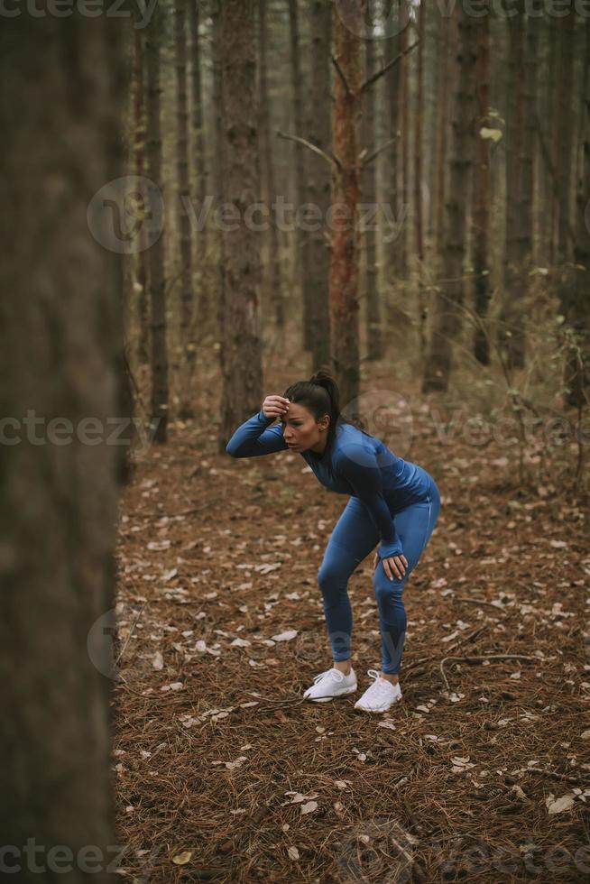 ung kvinna ta en paus under utomhusträning på skogsstigen på hösten foto