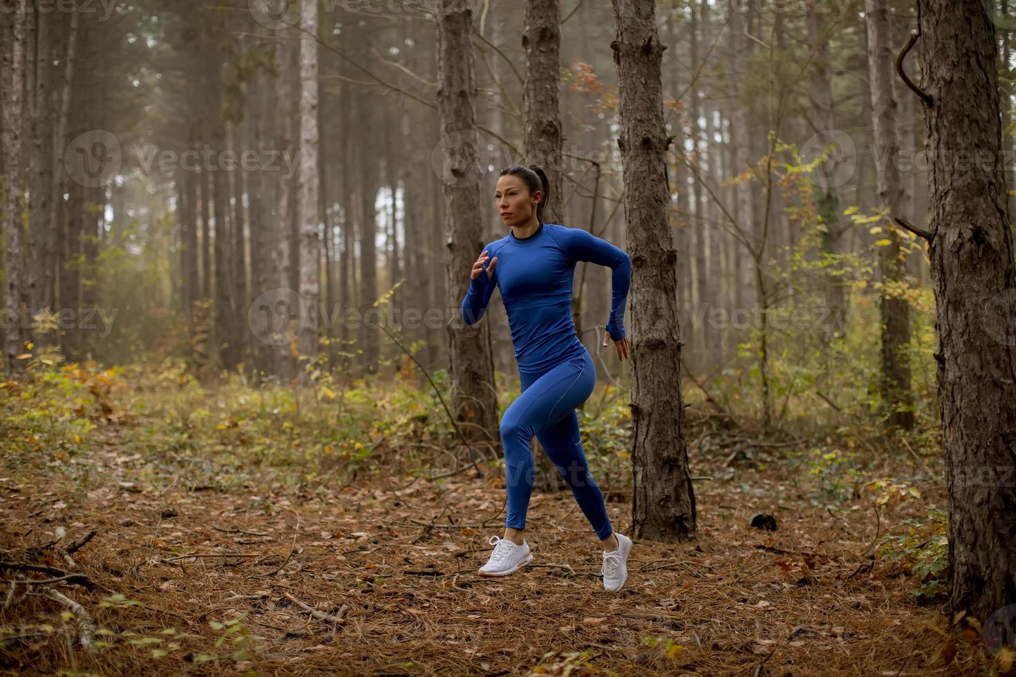 ung kvinna som kör på skogsstigen på hösten foto