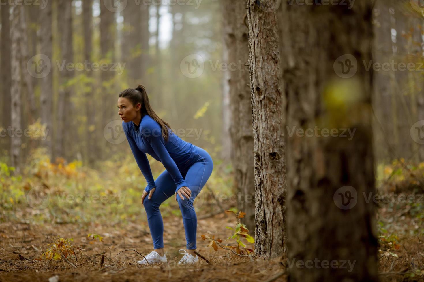 ung kvinna ta en paus under utomhusträning på skogsstigen på hösten foto