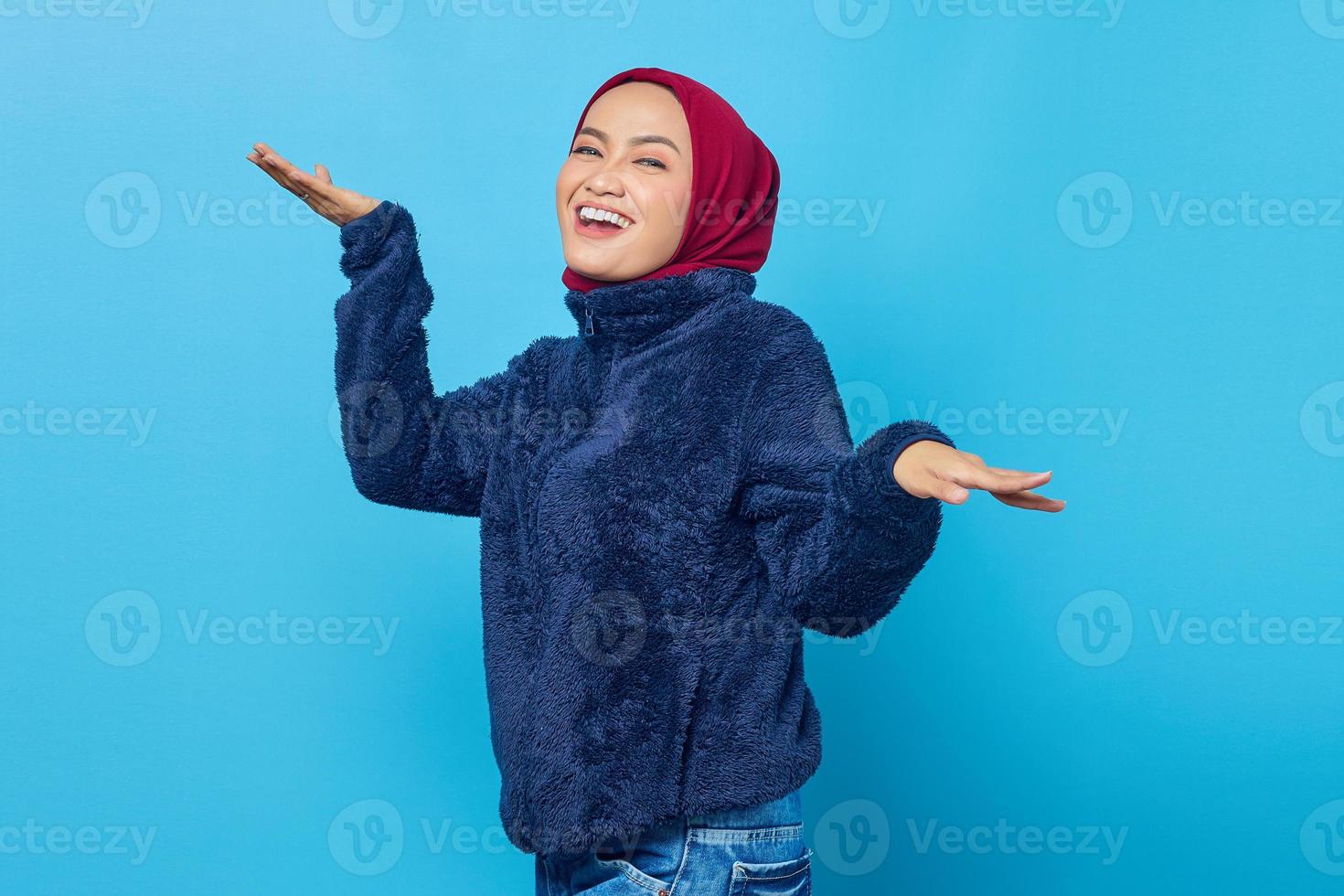 porträtt av vacker ung asiatisk kvinna som dansar glad och glad på blå bakgrund foto