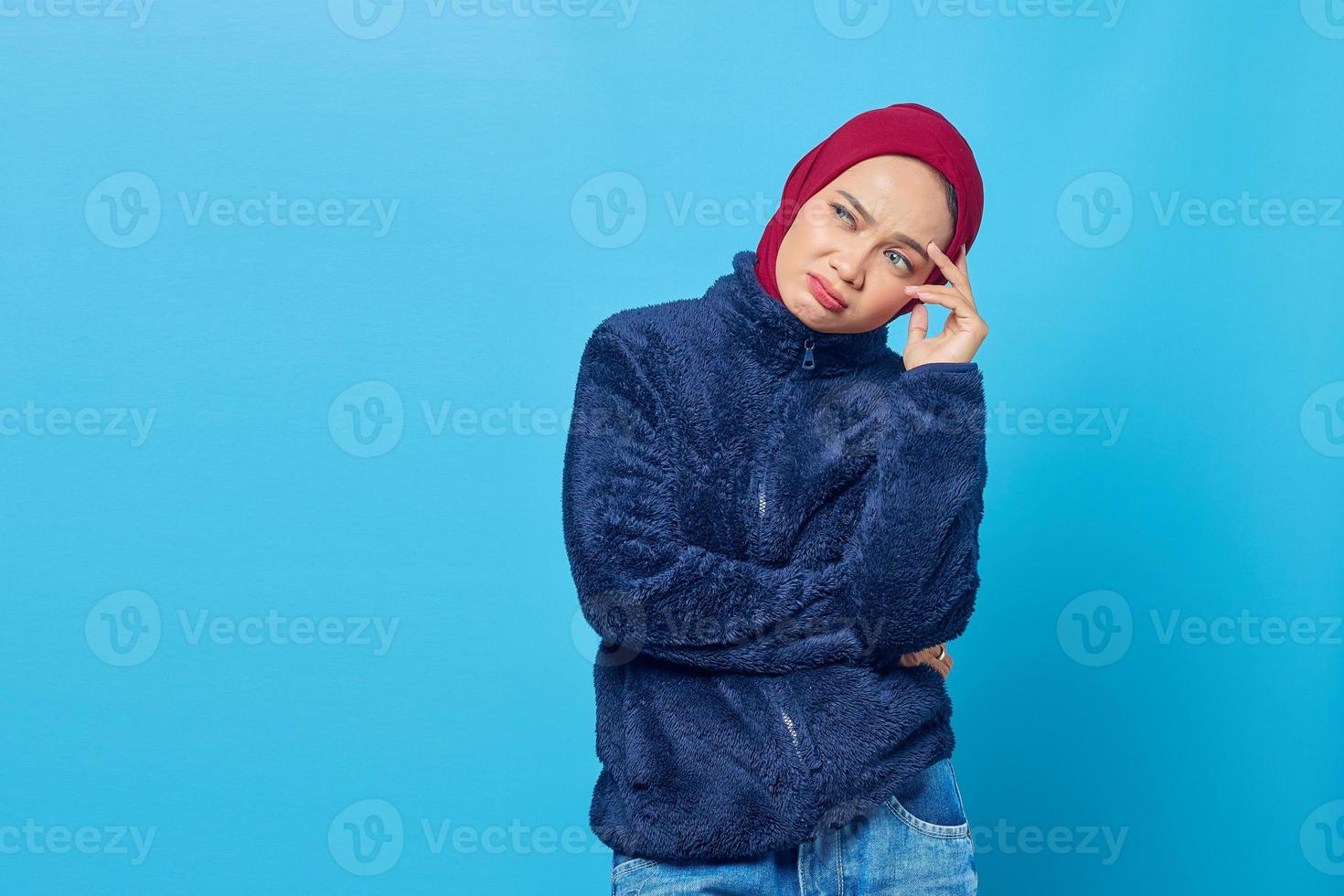 fundersam ung asiatisk kvinna tänker på något på blå bakgrund foto