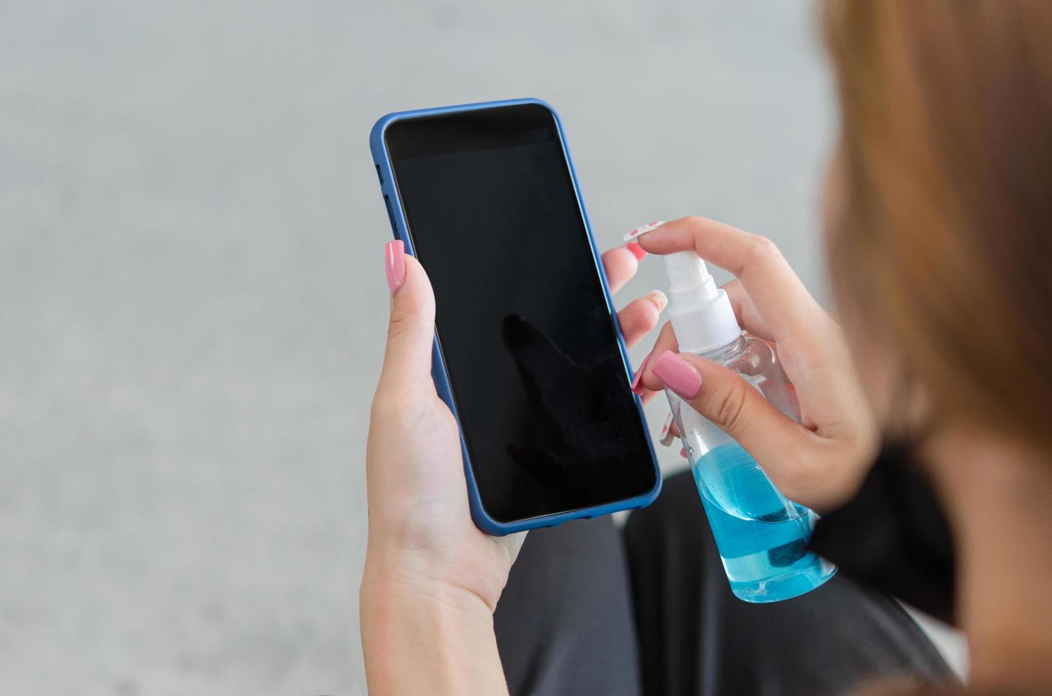 torka och desinficera din mobiltelefon med alkohol. begreppet hälso- och sjukvård för att förebygga sjukdom. kvinna som håller smart telefon. foto