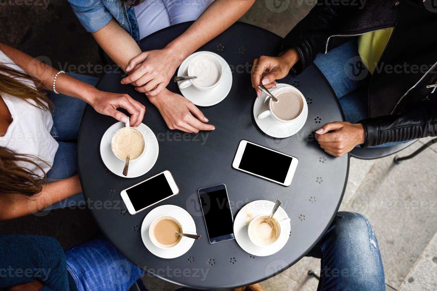 händer med kaffekoppar och smartphones i ett urbant kafé. foto