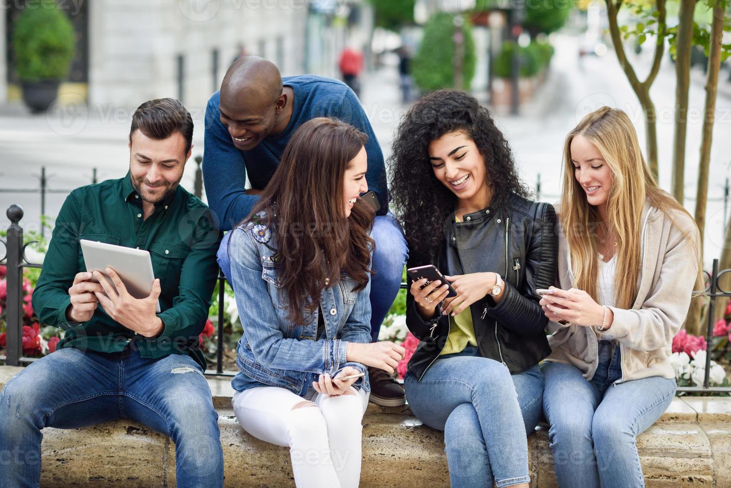 multietniska ungdomar som använder smartphones och surfplattor utomhus foto