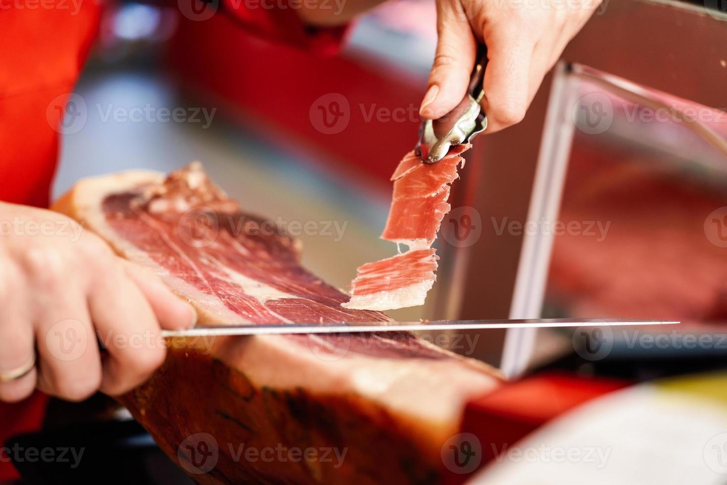 professionell skärare som skär skivor från en hel serranoskinka med ben foto