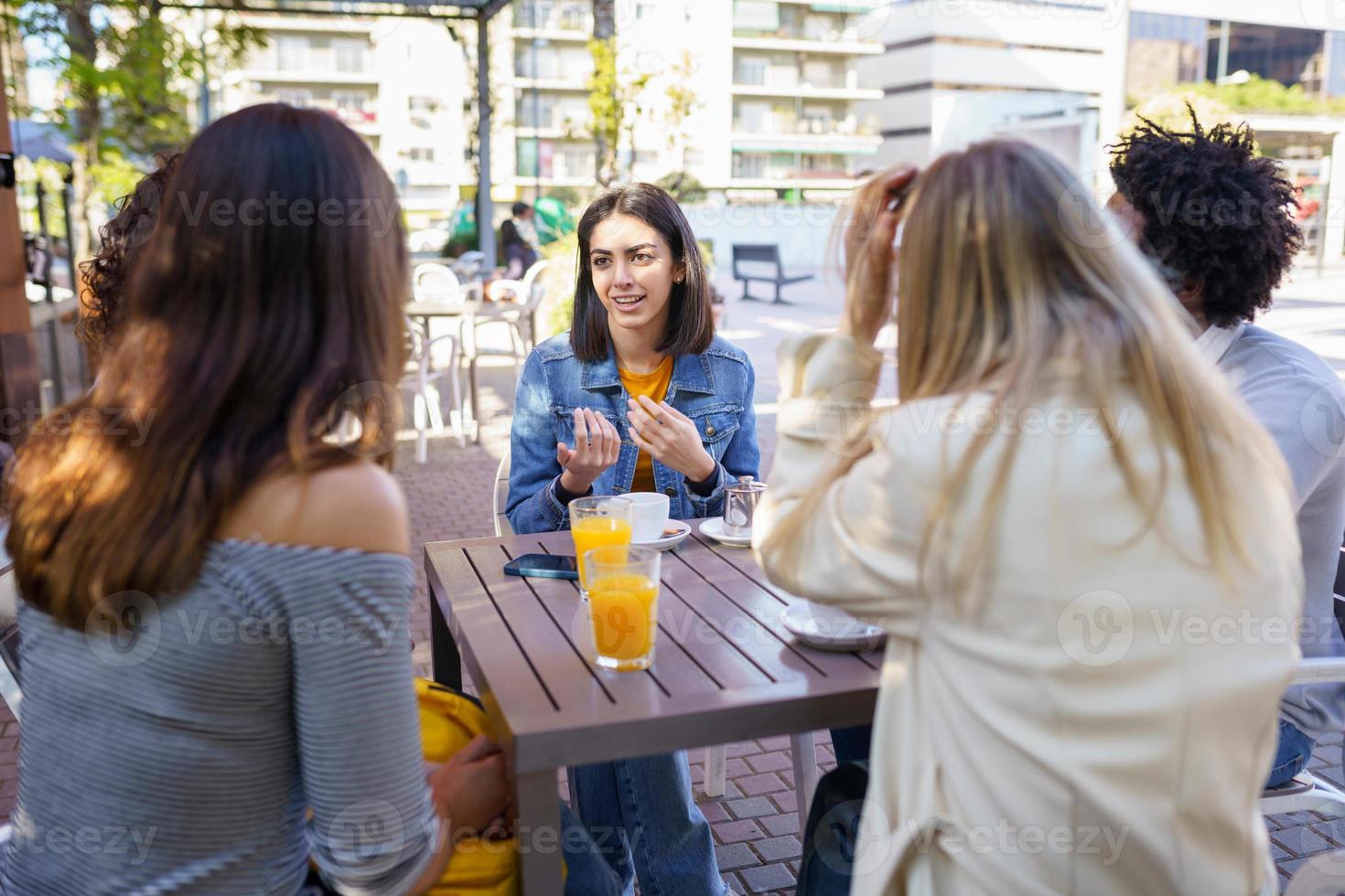 multietnisk grupp vänner som tar en drink tillsammans i en utomhusbar. foto