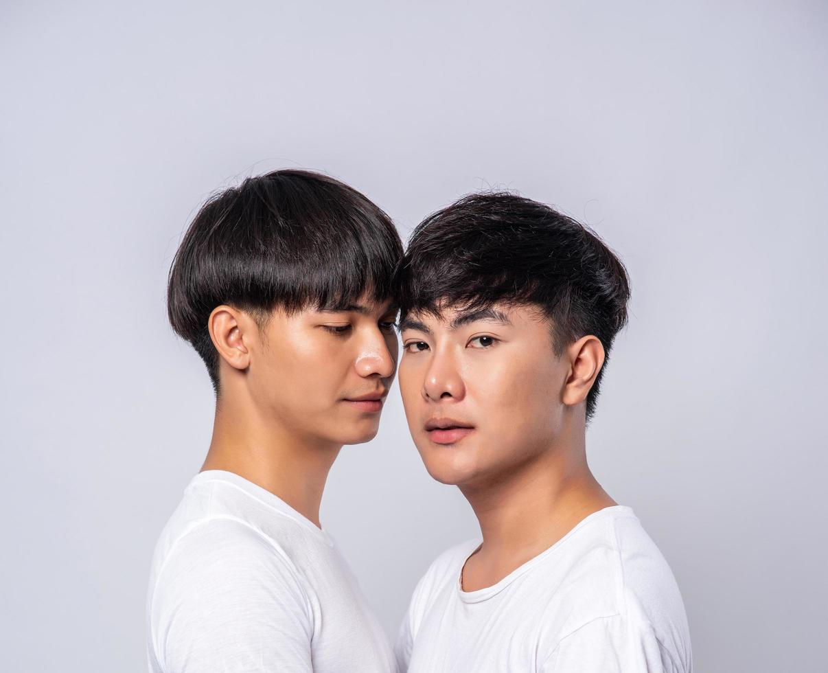 två förälskade män klädda i vita t-shirts tittade på varandras ansikten. foto