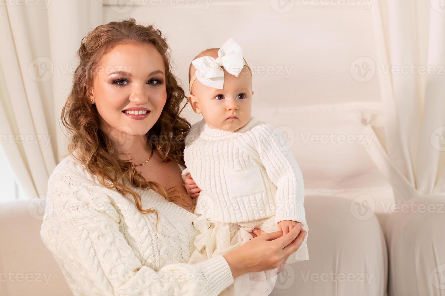 närbild porträtt av en skön mor med en liten dotter i henne vapen. Lycklig familj begrepp. mor spelar med henne dotter i en ljus rum foto