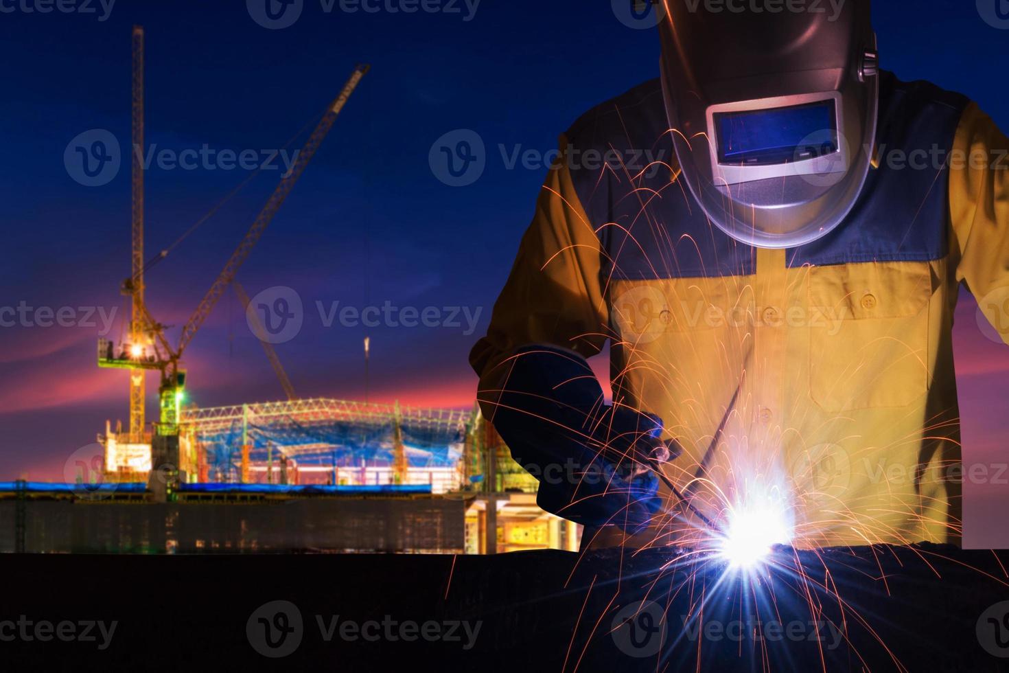 industriarbetare som svetsar stålkonstruktion för infrastrukturbyggnadsprojekt med byggarbetsplats i bakgrunden. foto