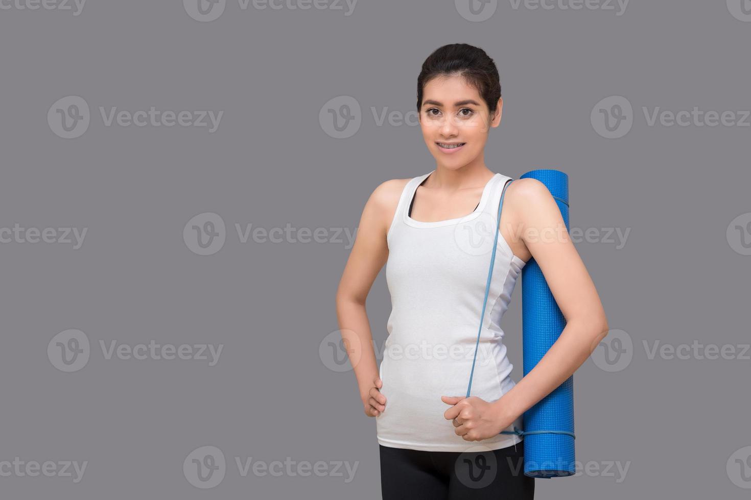 ung asiatisk kvinna som håller sin yogamatta på hälsosamt sportgym. yoga och meditation har goda fördelar för hälsan. fotokoncept för yogasport och hälsosam livsstil foto