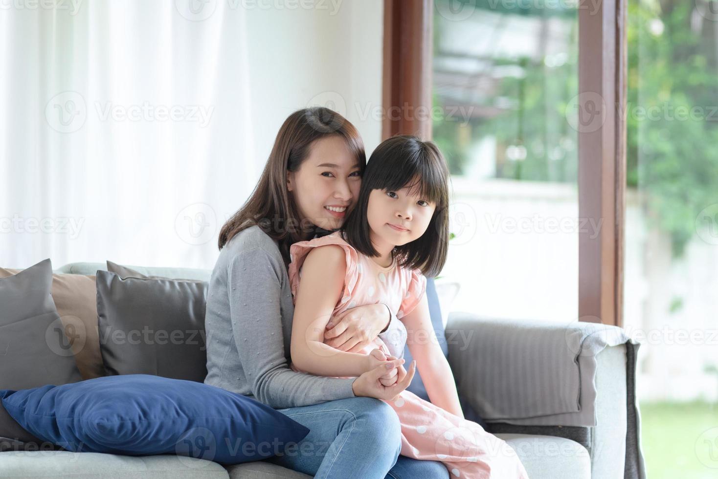 asiatisk mamma känner glädje under kram sin söta dotter med kärlek och omsorg hemma foto