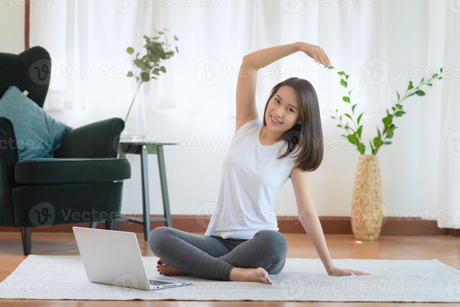 vacker asiatisk kvinna som håller sig i form genom att träna hemma för en hälsosam trendlivsstil foto