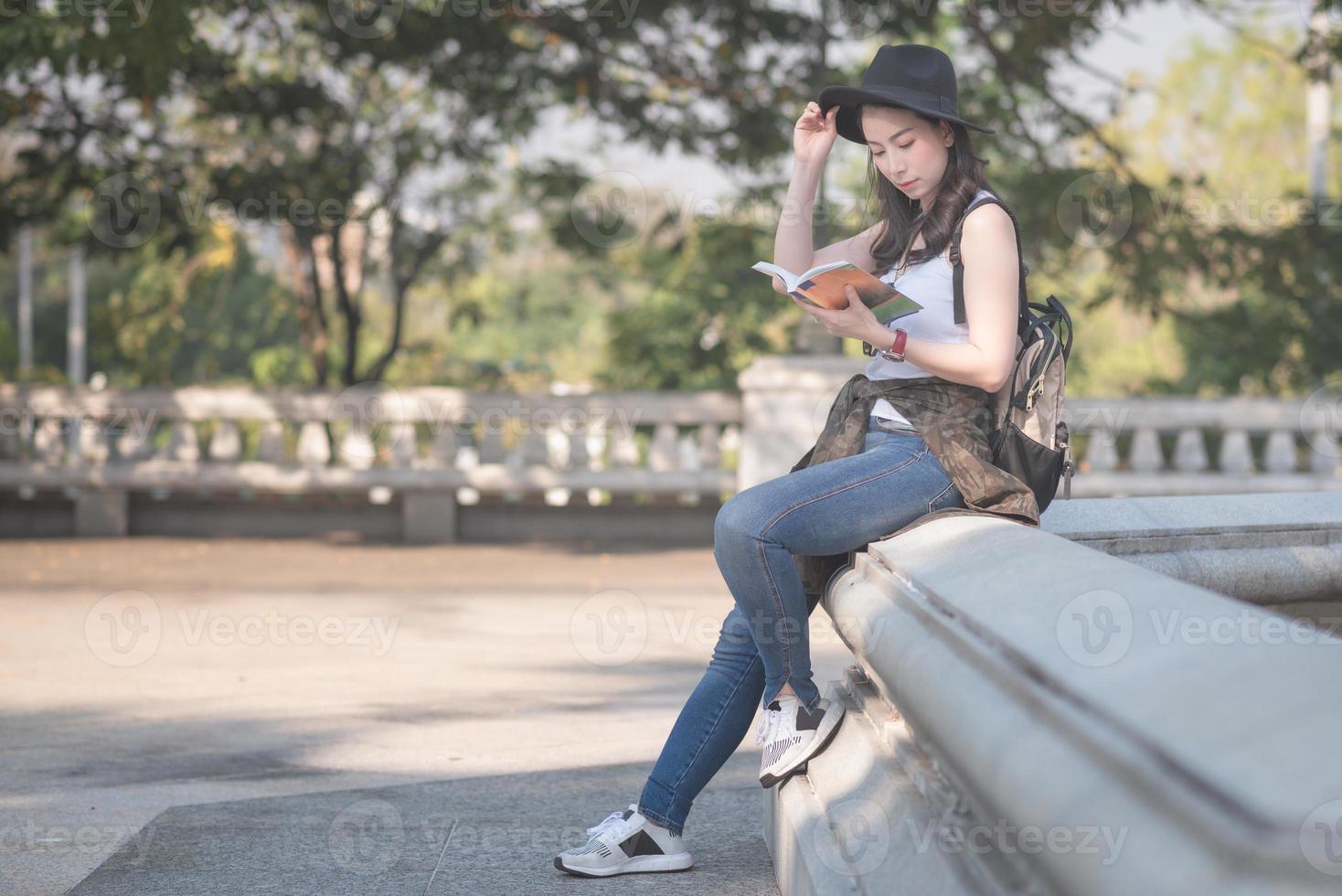 vacker asiatisk ensam turistkvinna som läser reseguideboken och letar efter sightseeingplats för turister. semesterresor på sommaren. foto