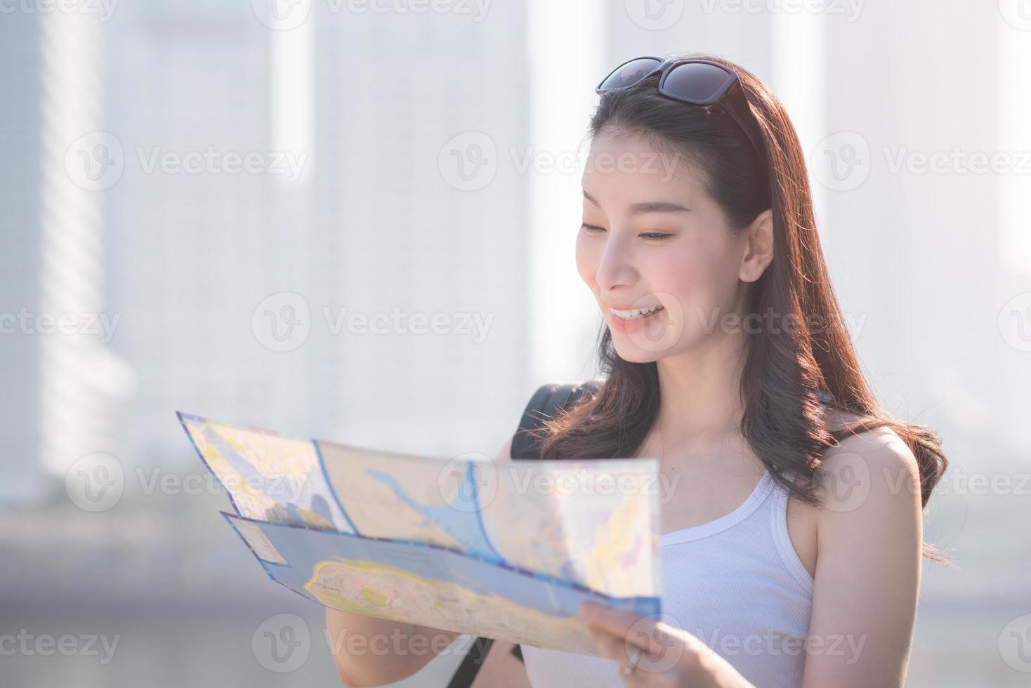 vacker asiatisk solo turist kvinna tittar på kartan söker efter turister sightseeing plats. semesterresor på sommaren. foto