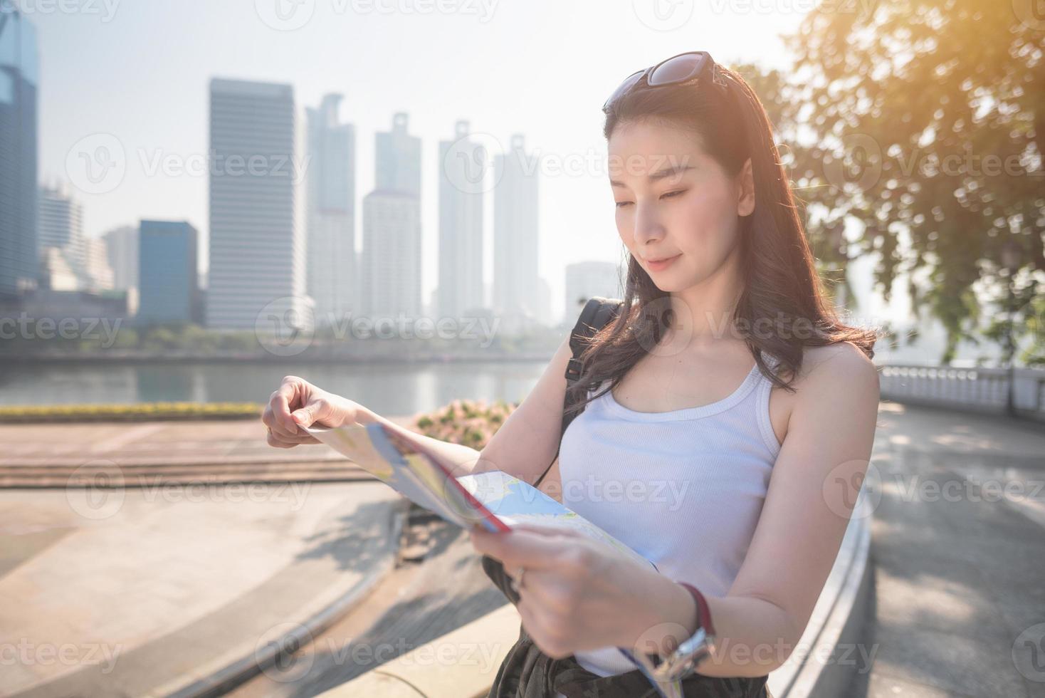 vacker asiatisk solo turist kvinna tittar på kartan söker efter turister sightseeing plats. semesterresor på sommaren. foto