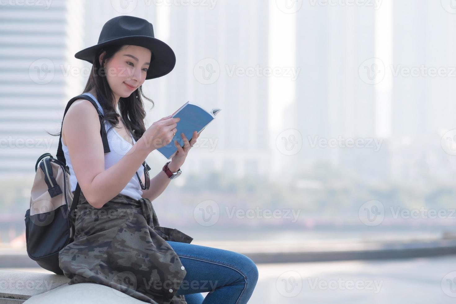 vacker asiatisk turistkvinna som läser reseguideboken och letar efter turisters sightseeingplats. semesterresor på sommaren. foto