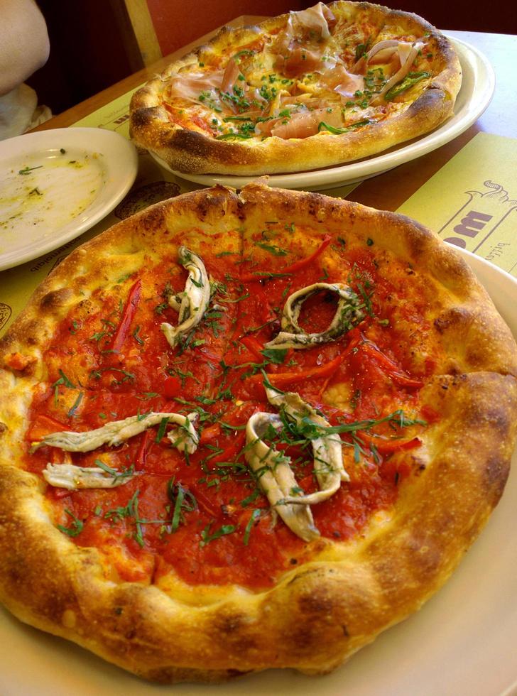 pizza kött cirkel skiva läckra heta pepperoni täckta tomater med prosciutto och kryddor på tallrik. foto