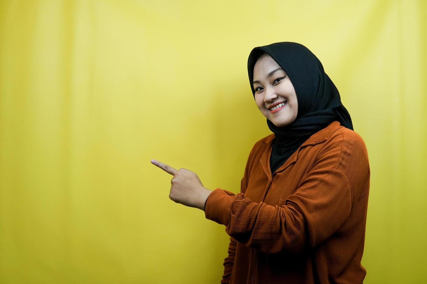 vacker ung asiatisk muslimsk kvinna med händer som pekar på tomt utrymme, presenterar något, isolerat foto