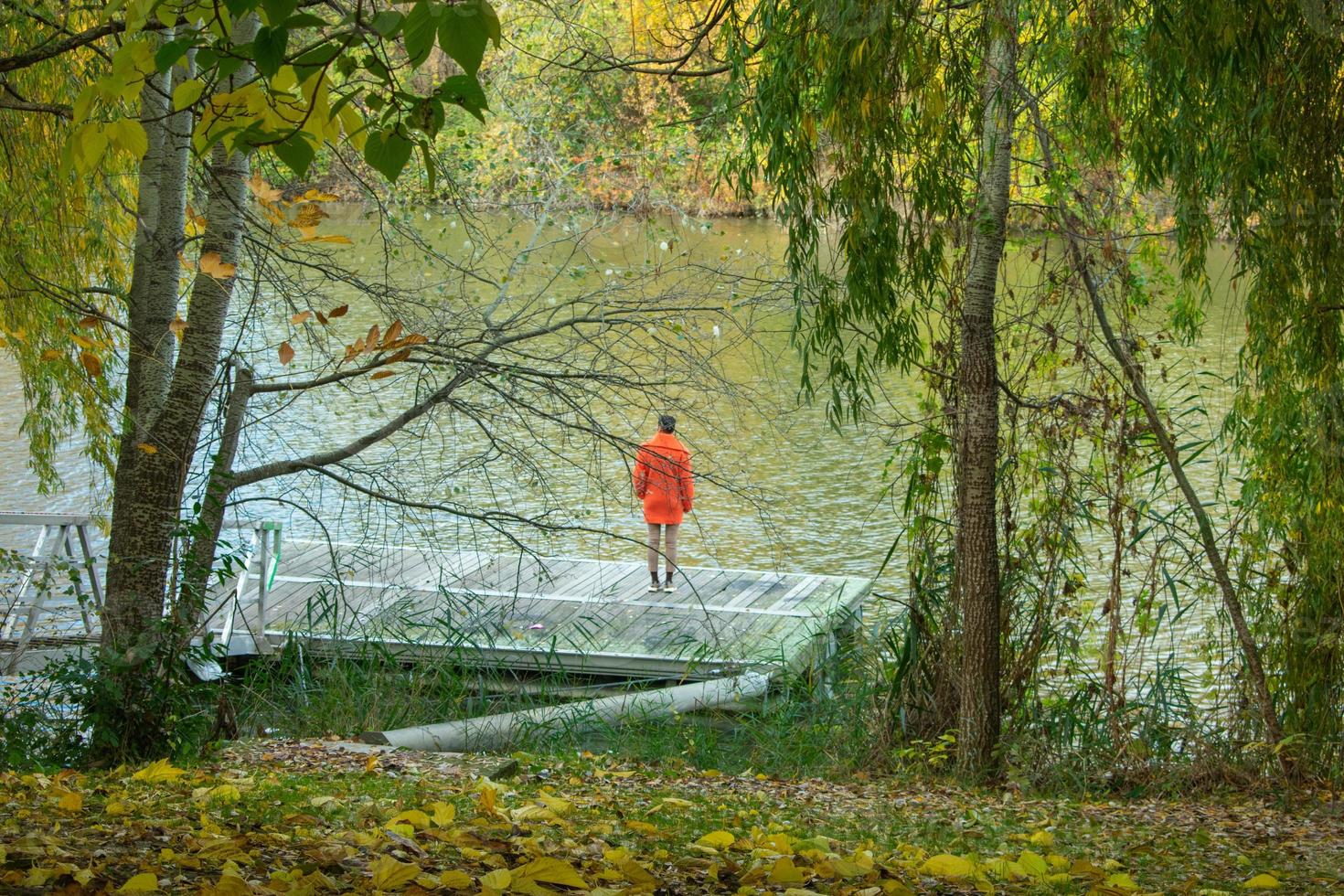 elegant kvinna i orange rock tittar på flodstranden foto