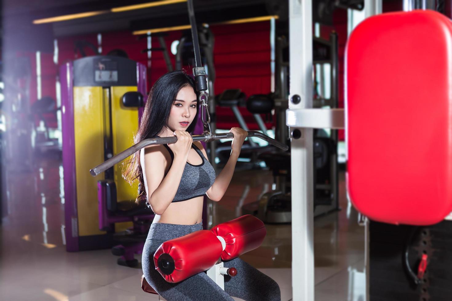fitness asiatiska kvinnor utför gör övningar träning av axel- och bröstmusklerna i sport gym interiör och hälsoklubb. foto