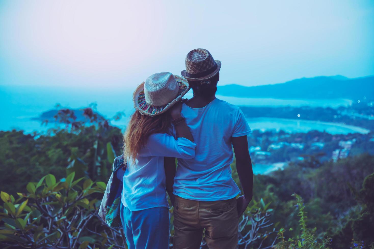 medelålders lyckliga romantiska par resor koppla av stranden i semestern och stående tittar på solnedgången. i sommar foto