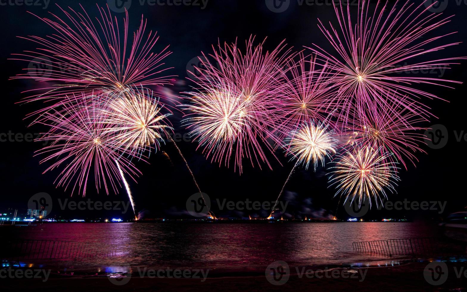 fantastiskt vackert färgstarkt fyrverkeri på festkvällen, som visas på havsstranden med flerfärgad reflektion på vatten foto