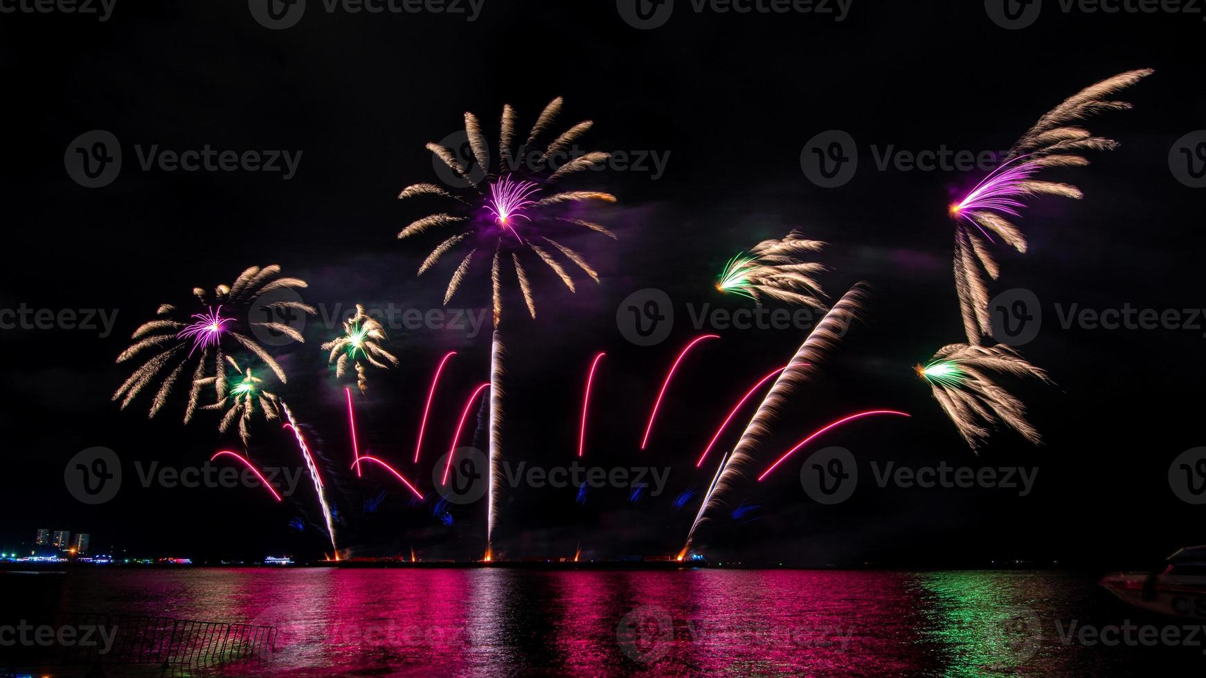 fantastiskt vackert färgstarkt fyrverkeri på festkvällen, som visas på havsstranden med flerfärgad reflektion på vatten foto