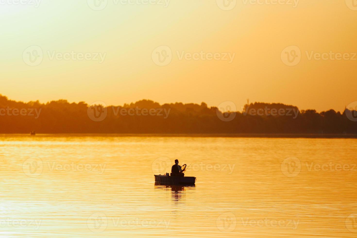 fiskare i en båt under solnedgången foto