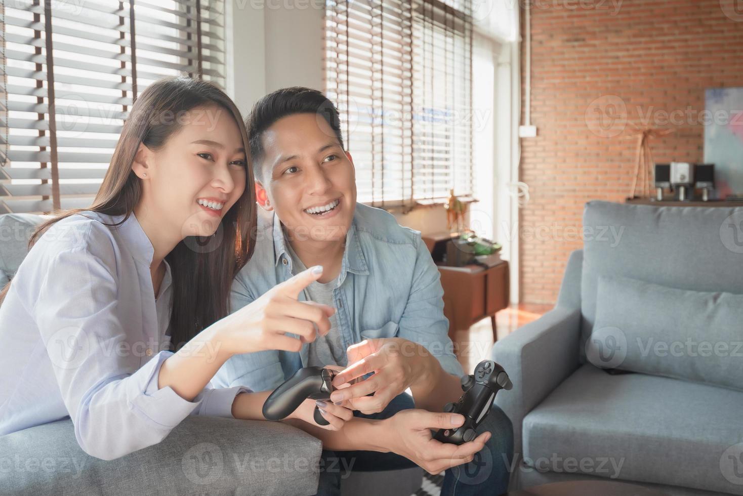 Asiatiska parälskare njuter och spelar konsolspel på semestern gör mer kvalitetstid av lycka tillsammans hemma foto
