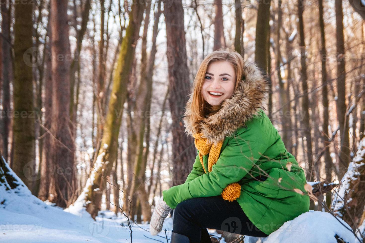 vacker ung flicka i en vinterskog. vinterporträtt av kvinnor klädda i vantar och halsduk foto
