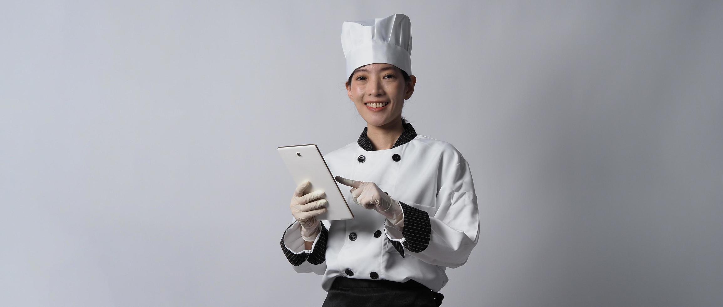 asiatisk kvinna kock håller smartphone eller digital surfplatta och fick beställning från online foto
