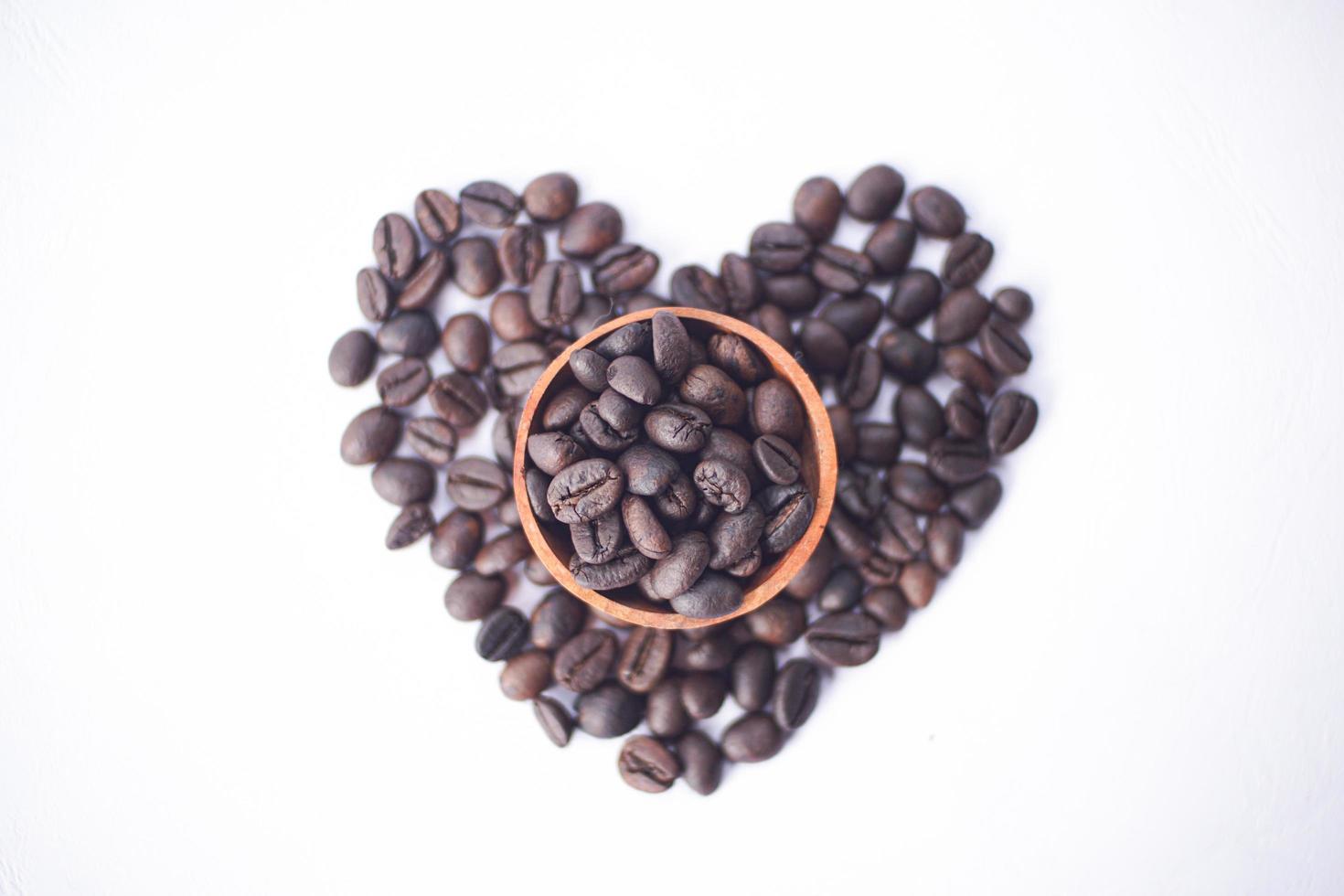 kaffebönor på en träskål med kärleksform foto