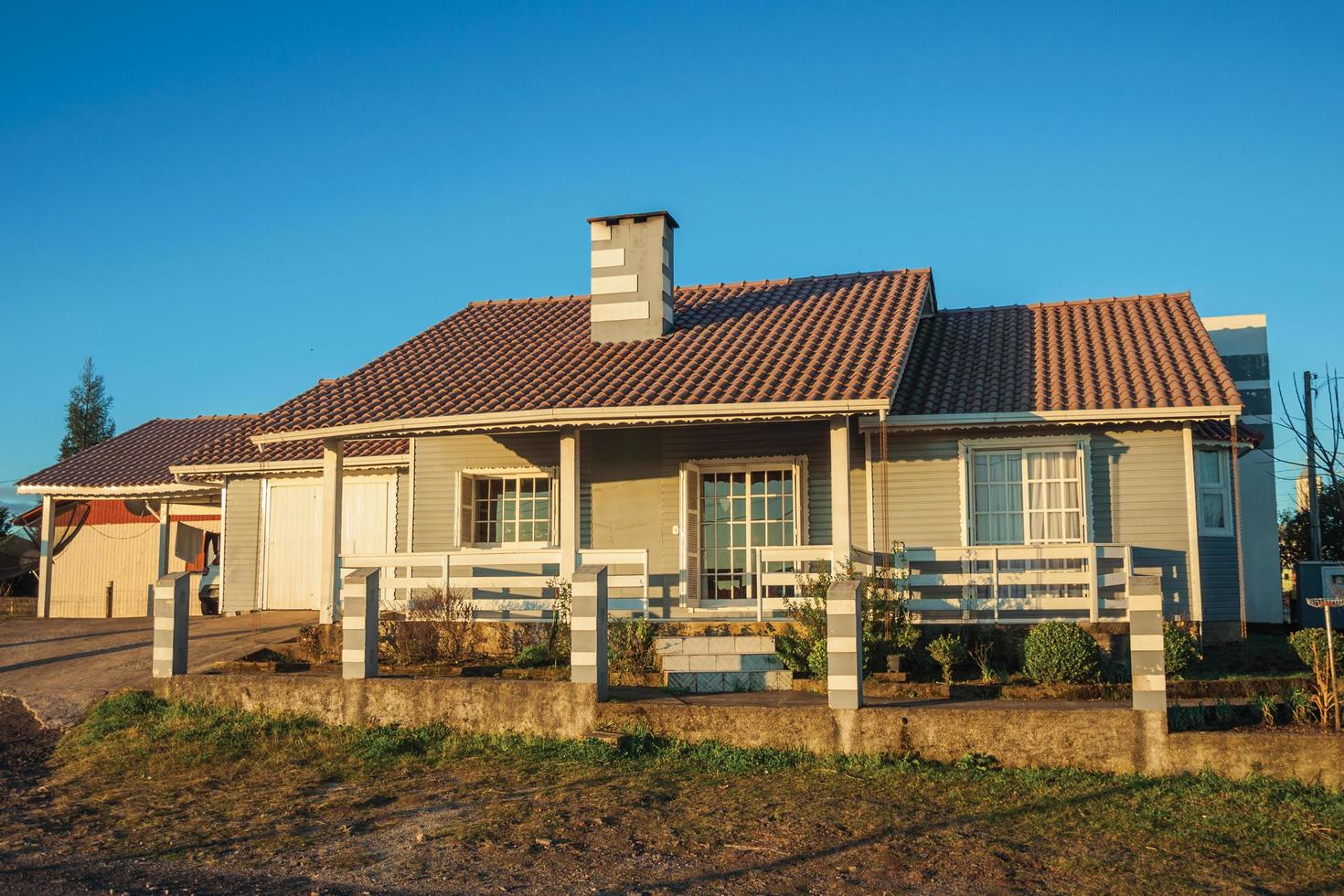 cambara do sul, Brasilien - 16 juli 2019. charmigt modernt radhus med staket och trädgård i solnedgången, på en grusgata i cambara do sul. en liten lantstad med fantastiska naturliga turistattraktioner. foto