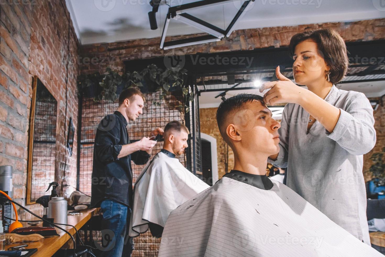 frisörer klipper sina kunder i barbershop. reklam och frisersalong koncept foto